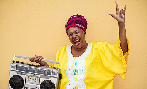 mature woman holding boom box, doing hang loose hand gesture